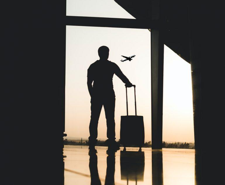 silhouette of man holding luggage inside airport