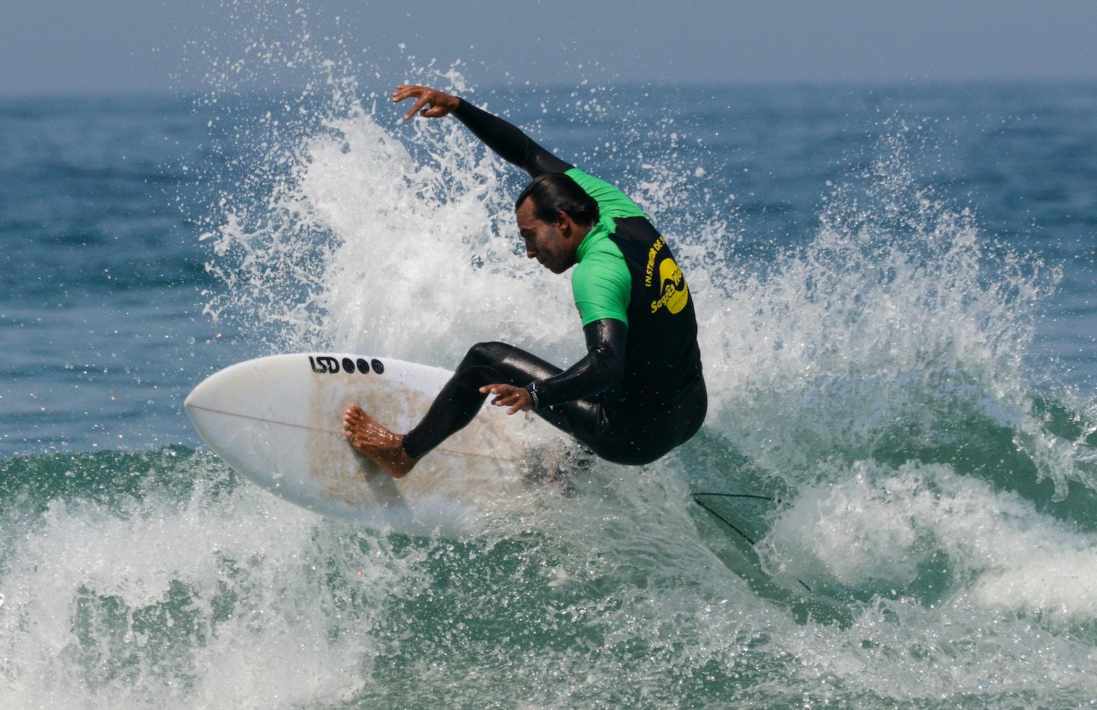 man in green and black wet suit surfing on sea waves during daytime