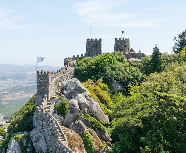 a very tall castle sitting on top of a lush green hillside