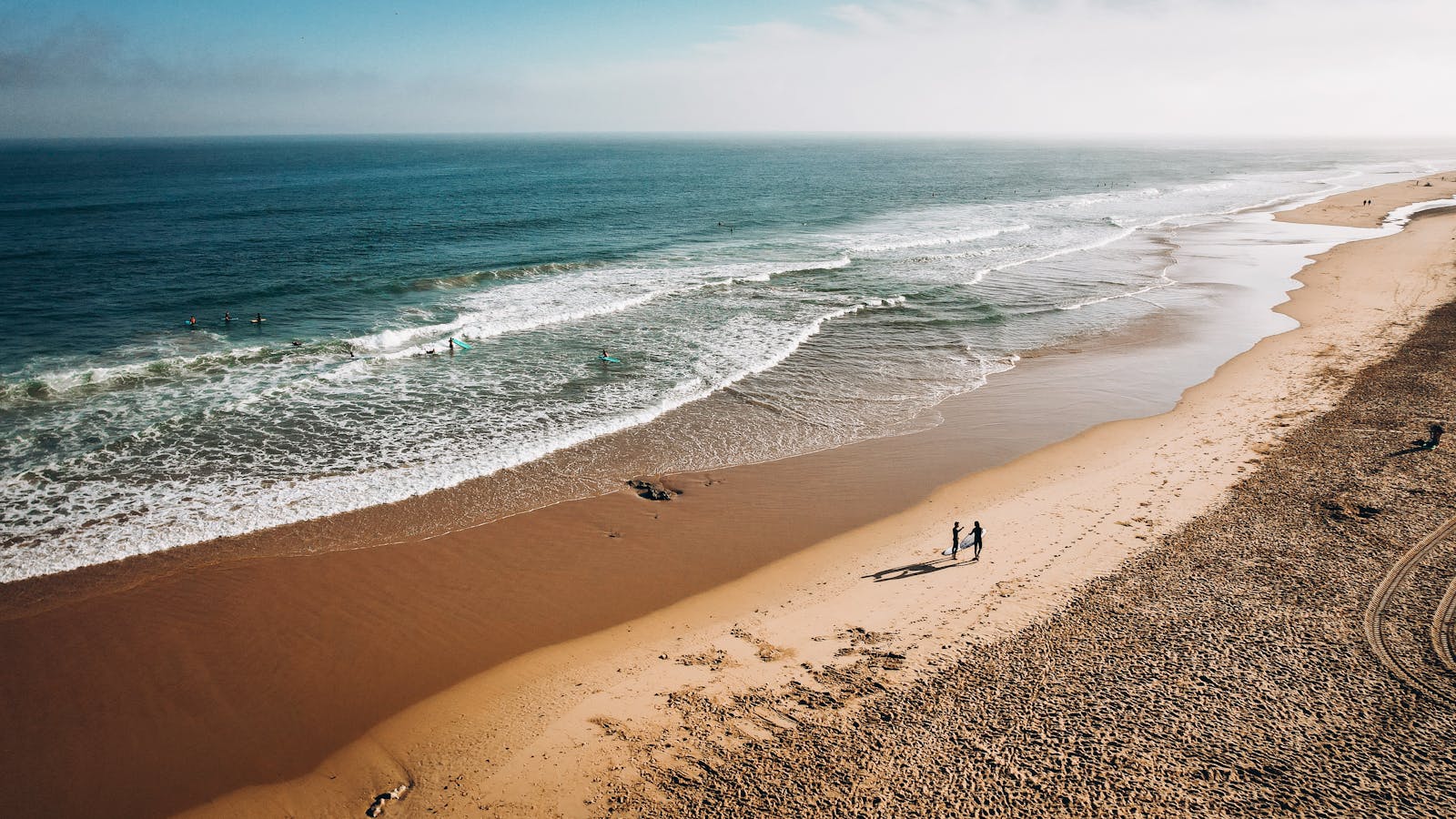 Stunning aerial shot of Cascais beach in Lisbon, capturing surf and sand under the summer sun.
