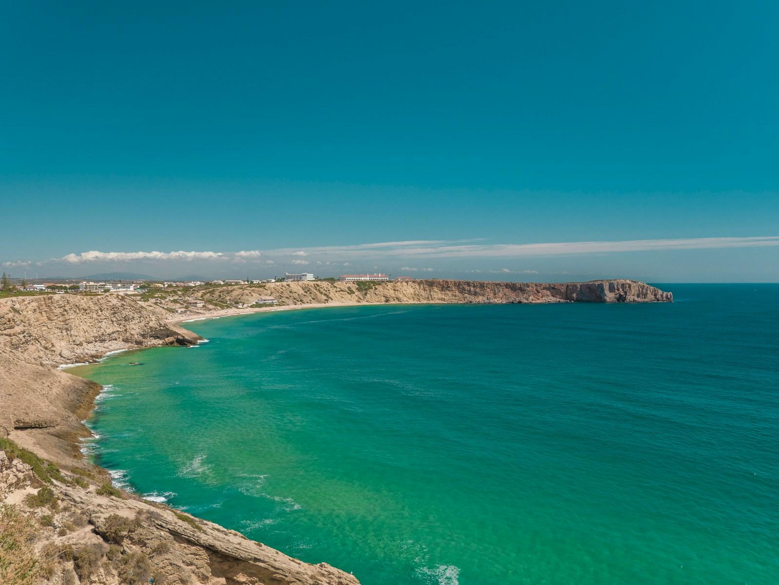 blue sea beside brown mountain under blue sky during daytime