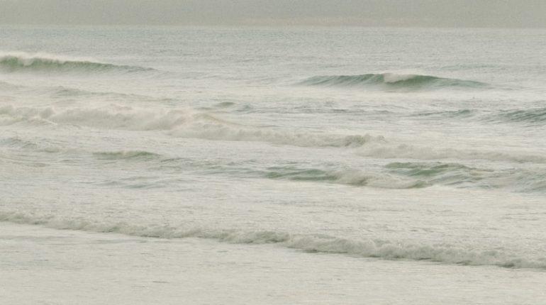 Surfer walks towards the ocean waves.