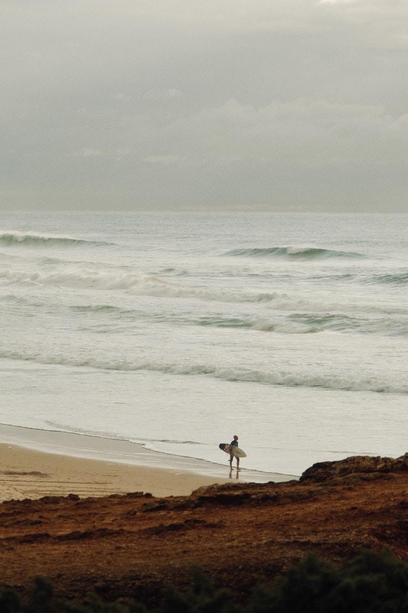 Surfer walks towards the ocean waves.